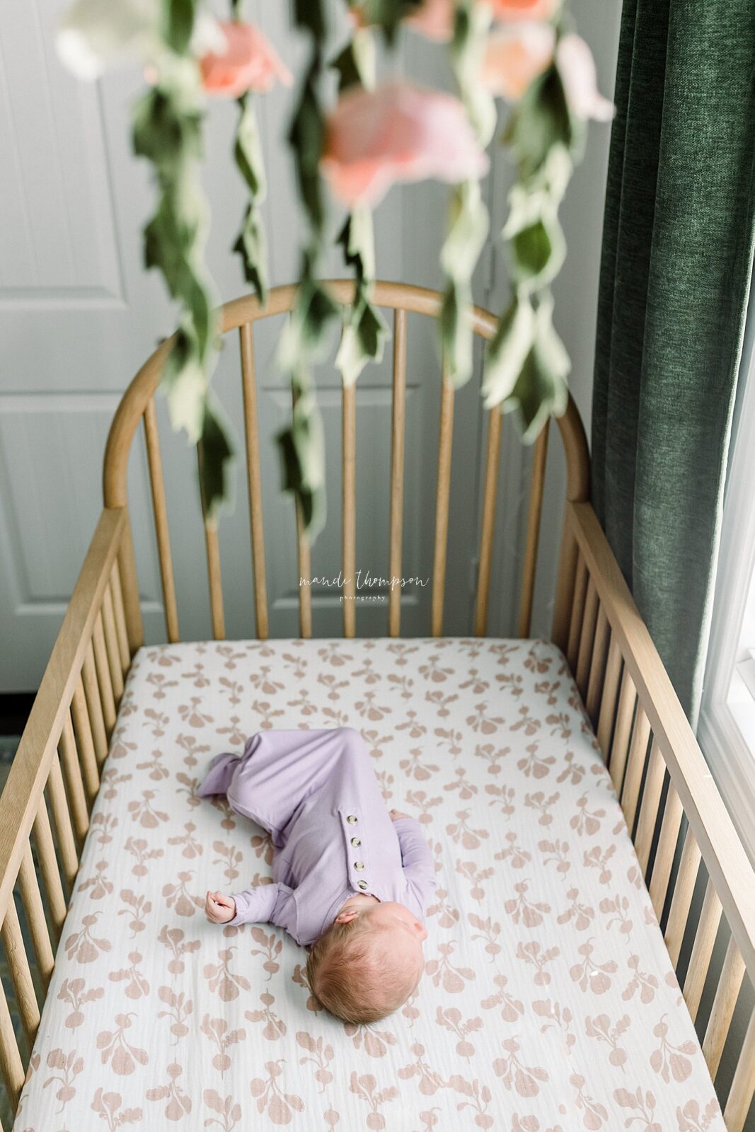 sleepy baby in her crib with beautiful floral decor