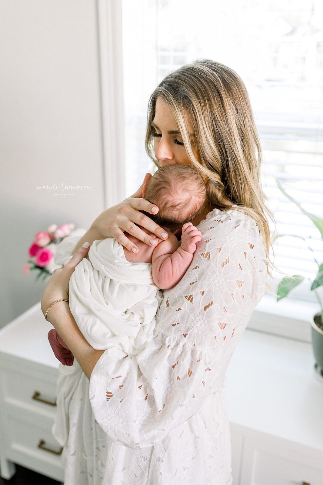 Mom lovingly holding their newborn baby together in cozy Katy, Texas nursery