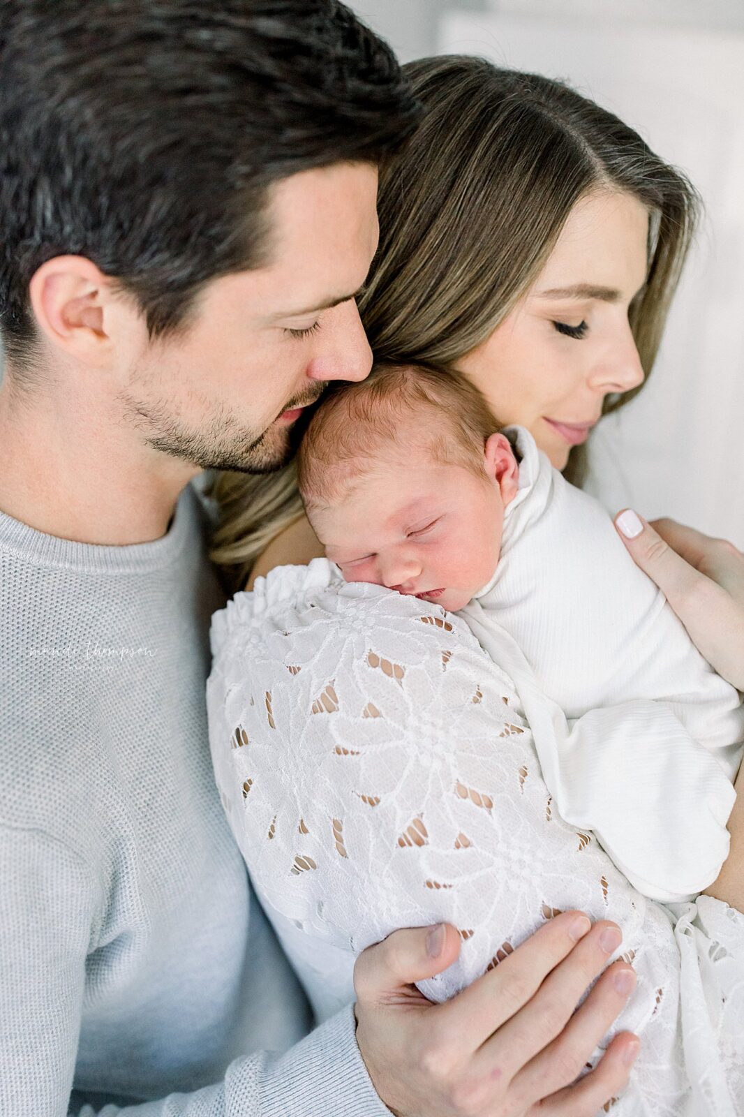 Mom and dad cuddling their newborn baby in a peaceful moment during in-home session in Katy, Texas