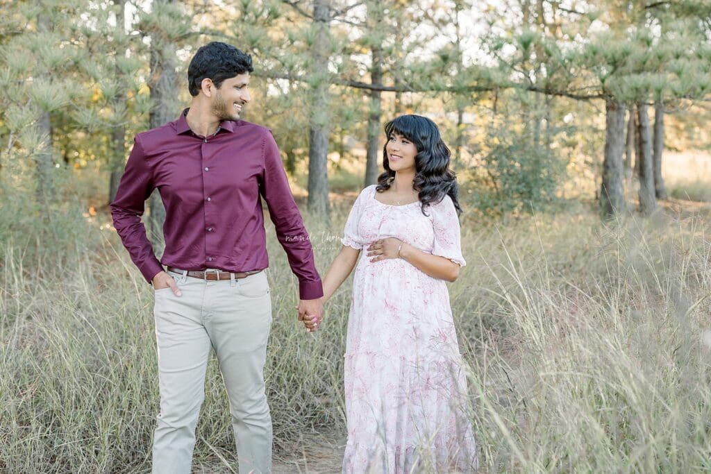 Mom and dad walking hand-in-hand outdoors during maternity session Katy TX