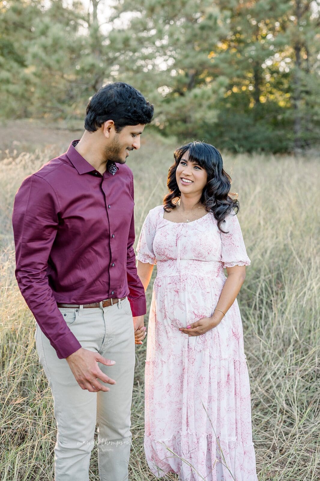 expecting parnents walking hand-in-hand outdoors during maternity session Katy TX