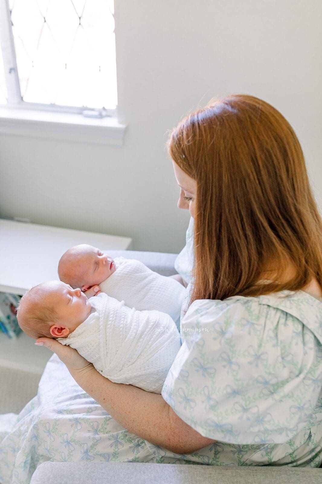 Mom holding twin newborn babies in neutral swaddles during in-home newborn session Katy TX
