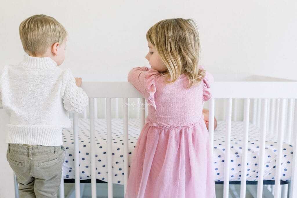 siblings looking into the crab at their newborn baby brothers in katy texas 