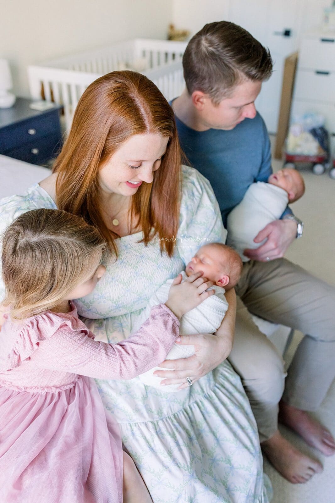 Mom holding newborn baby with family in nursery Katy TX